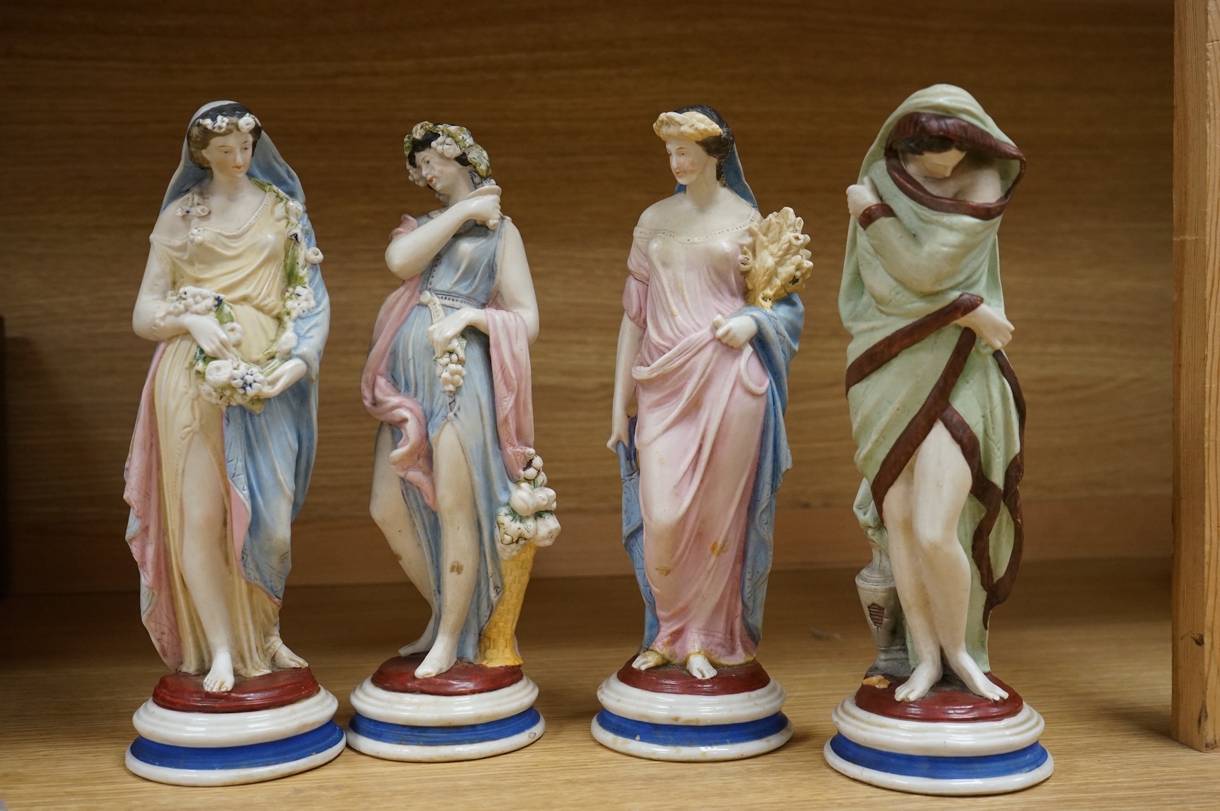 A set of four painted biscuit porcelain figures of The Seasons, and a silver-mounted scent bottle, figures 24cm